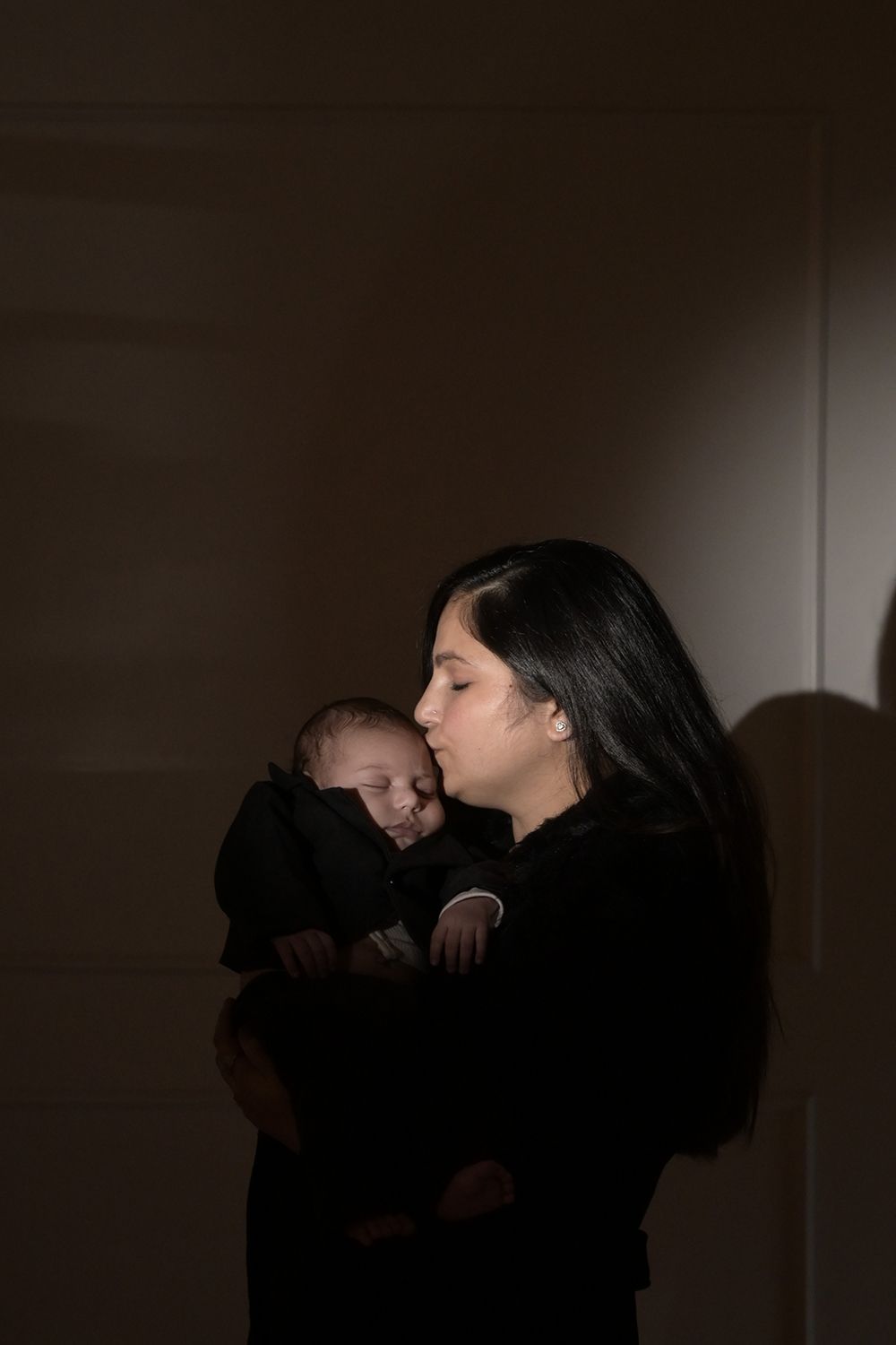 Mother holding and kissing her newborn baby